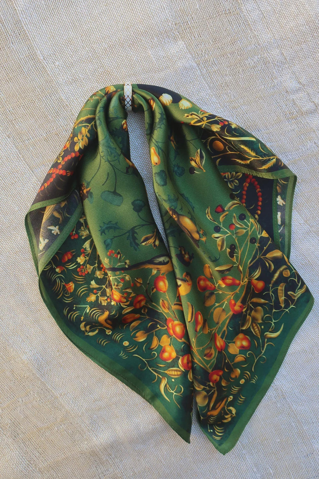 Green scarf with floral pattern on a beige fabric background