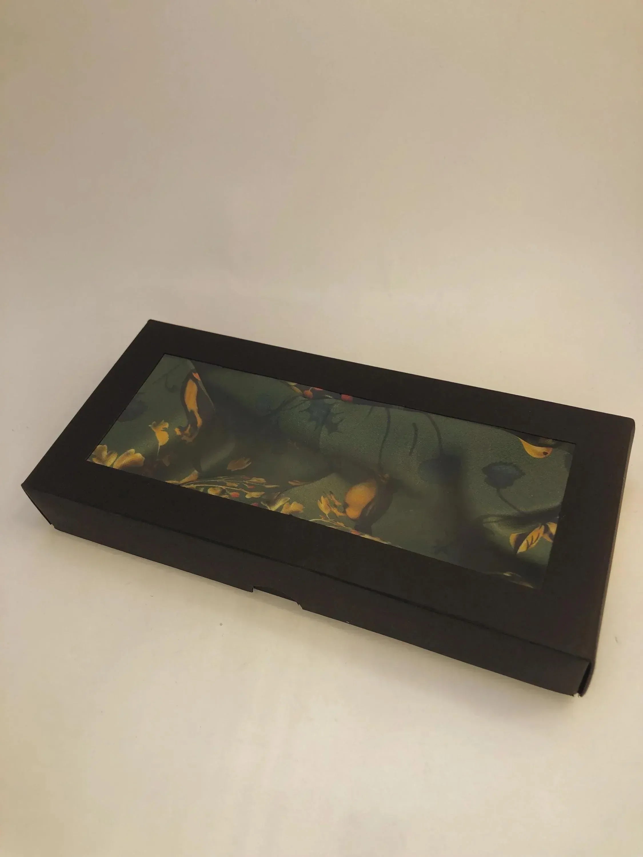 Black gift box with a green fabric interior on a white background