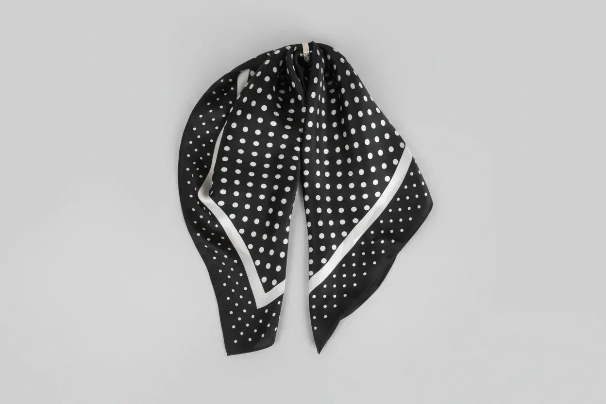 Black and white polka dot headscarf on a light gray background