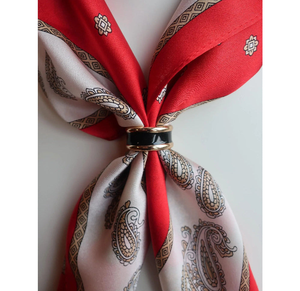 Red and white patterned scarf tied into a knot with a decorative ring on a light background